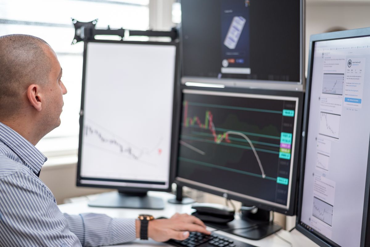 Professional investor studying financial charts across multiple monitors